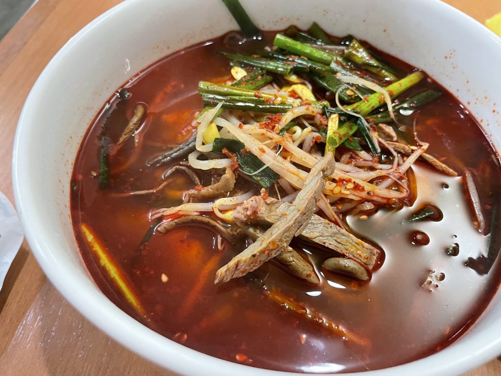 辛そうな赤いスープに、牛肉、豆もやし、ニラなどの具材がたっぷり入った韓国料理のユッケジャン