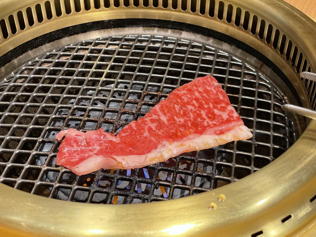 網の上で焼かれる、サシの入った鮮やかな赤身の牛肉