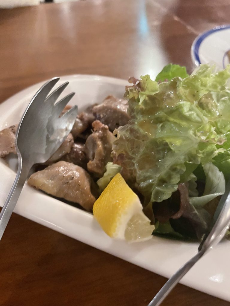 砂肝のコンフィ。フレッシュなレタスとカットレモンが添えられている。