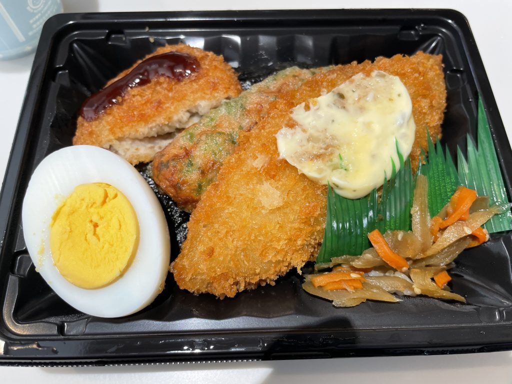 白身魚のフライ、メンチカツ、ゆで卵、ちくわの磯辺揚げが入ったお弁当のおかず
